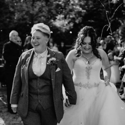 Black and white photo of two brides walking down confetti aisle at The Shropshire Wedding Venue Telford