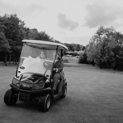Black and white photo of two brides driving a golf buggy at The Shropshire Wedding Venue