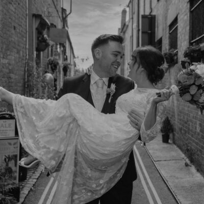Black and white image of groom holding bride in rural alleyway Black and white photo of bride and groom during first dance at Hadley Park House photographed by Shropshire Wedding Photographer R&R Photography