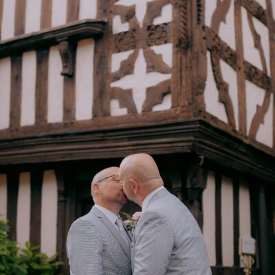 LGBTQ+ wedding of two grooms kissing in front of Albright Hussey Hotel Shropshire Wedding Photography